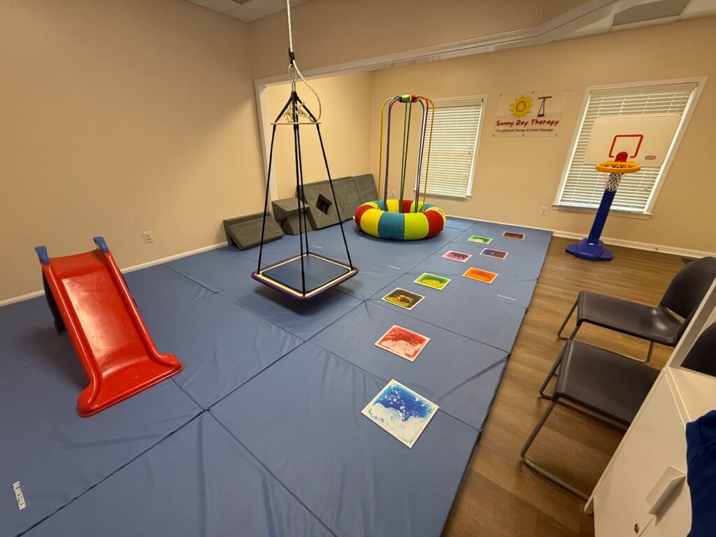 sensory integration therapy swing, jumping device (Jump a roo), lava tiles, slide, basketball goal in sensory gym for pediatric therapy