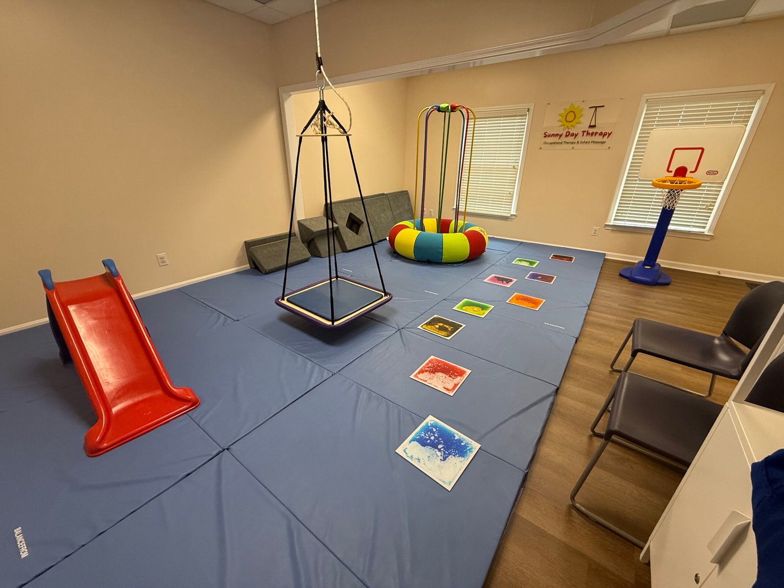 sensory integration therapy swing, jumping device (Jump a roo), lava tiles, slide, basketball goal in sensory gym for pediatric therapy